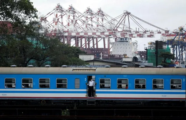 A man travels in a train as the Colombo harbour is seen, amid the country's economic crisis in Colombo, Sri Lanka, April 20, 2022. (Photo by Dinuka Liyanawatte/Reuters)
