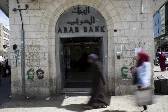 Palestinians walk past a bank in the West Bank city of Ramallah March 25, 2015. (Photo by Mohamad Torokman/Reuters)