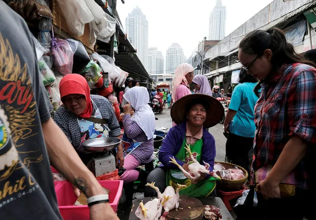 A woman seller (C) offers a chicken to a customer at a vegetable market in Jakarta, Indonesia, June 2, 2017. (Photo by Reuters/Beawiharta)