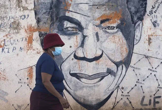 A woman wearing a mask walks past a mural of former South Africa's president Nelson Mandela, in Katlehong, east of Johannesburg, South Africa, Friday, April 29, 2022. South Africa's health minister says it is likely the country has entered a new wave of COVID-19 earlier than expected as new infections and hospitalizations have risen rapidly over the past two weeks. (Photo by Themba Hadebe/AP Photo)