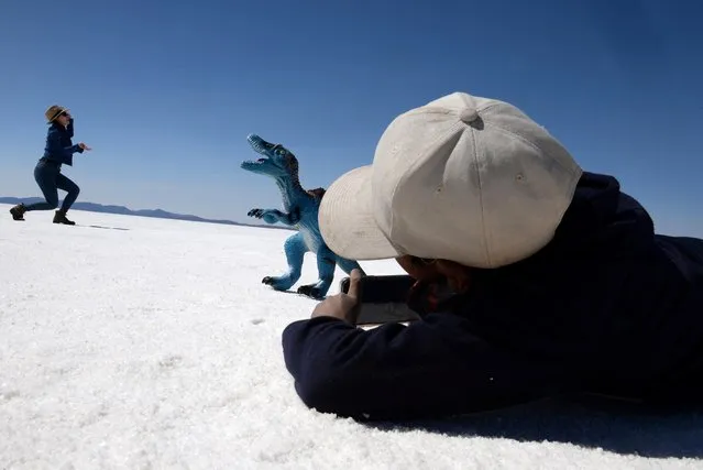 Piter Condori, 11, takes pictures of a tourist to earn money for his family, at the Uyuni Salt Flat in Bolivia on March 27, 2022. (Photo by Claudia Morales/Reuters)