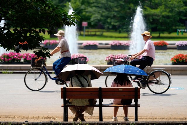 People holding parasols sit on the bench under an intense sun at a park in Tokyo, Monday, July 8, 2024. Hot weather on Monday has set with temperatures rising up over 35 degrees Celsius (95 degrees Fahrenheit) in Tokyo, according to the Japan Meteorological Agency. (Photo by Eugene Hoshiko/AP Photo)