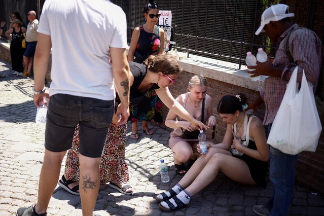 A tourist from the UK receives help near the Colosseum after fainting during a heatwave across Italy, in Rome, Italy on July 11, 2023. (Photo by Guglielmo Mangiapne/Reuters)