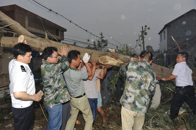 Rescue workers lift a tree trunk after a tornado hit Yancheng, Jiangsu province, China, June 23, 2016. (Photo by Reuters/Stringer)