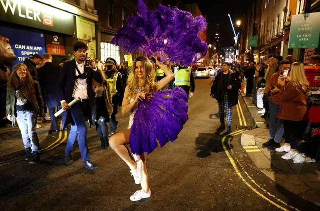 A woman dances with purple feathers in the West End of London after pubs close, before London moves into the highest tier of coronavirus restrictions from Wednesday as a result of soaring case rates, Tuesday December 15, 2020. (Photo by Henry Nicholls/Reuters)