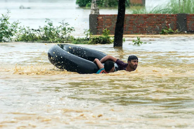 Nepali residents swim with a rubber ring in a flooded area in the Birgunj Parsa district, some 200km south of Kathmandu, on August 13, 2017. Floods and landslides caused by torrential monsoon rains have killed at least 40 people in the last three days across Nepal, officials said on August 13. Heavy rains have hit more than a dozen districts in the country's far eastern region as well as some areas in the west since the morning of August 11, the home ministry said. (Photo by Manish Paudel/AFP Photo)