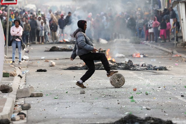 A protester blocks the streets with stones and rubble during an ongoing strike by taxi operators against traffic authorities, in Masiphumelele, Cape Town, South Africa on August 8, 2023. (Photo by Esa Alexander/Reuters)