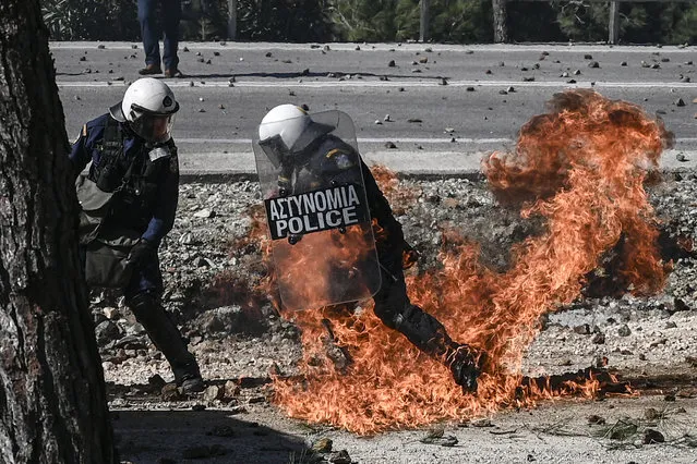 A Greek anti-riot police moves away from flames during clashes with demonstrators protesting against the construction of a new controversial migrant camp near the town of Mantamados on the northeastern Aegean island of Lesbos, on February 26, 2020. The Greek islands of Lesbos, Chios and Samos staged a general strike on February 26, as protests against the construction of new migrant camps intensified. For a second day, protesters on Lesbos faced off against riot police near the town of Mantamados, close to the site of a planned camp for up to 7,000 people. Small groups of protesters threw stones and firebombs at the police, who responded with tear gas and flash grenades. (Photo by Aris Messinis/AFP Photo)