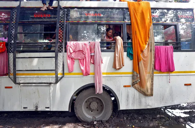 A Hindu pilgrim hangs clothes on iron rods tied to windows of a parked bus to dry on the banks of the river Ganges in Kolkata, August 17, 2017. (Photo by Rupak De Chowdhuri/Reuters)