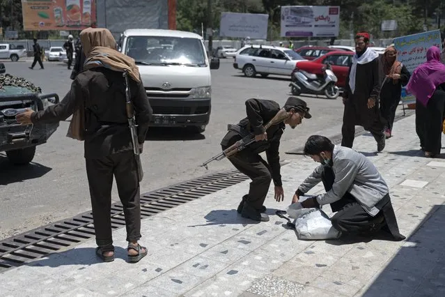 A Taliban fighter searches the belongings of a pedestrian along a blocked street ahead of the council meeting of tribal and religious leaders in Kabul on June 29, 2022. (Photo by Wakil Kohsar/AFP Photo)