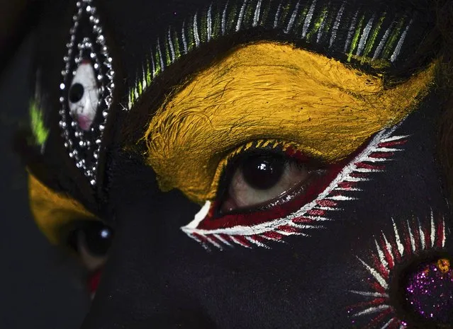 An Indian artist gets make up before a performance during a procession of “Bonalu” festival in Hyderabad, India, Monday, July 25, 2022. Bonalu is a month-long Hindu folk festival of the Telangana region dedicated to Kali, the Hindu goddess of destruction. (Photo by Mahesh Kumar A./AP Photo)