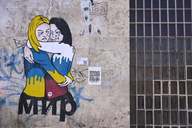 An anti-Ukraine war mural by Italian street artist known by the name of “Laika” depicting a hug between two women, one dressed in the Russian, the other in the Ukrainian national colors, respectively, above the word MIR (Peace), is painted on a wall in Rome, Italy, on International Women's Day, 08 March 2022. (Photo by Riccardo Antimiani/EPA/EFE)