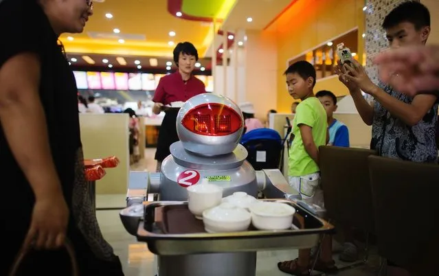 This photo taken on August 13, 2014, shows a robot carries food to a table of hungry customers. (Photo by Johannes Eisele/AFP Photo)