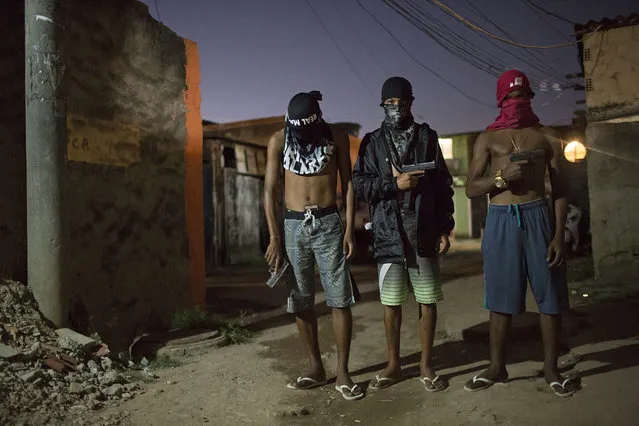 In this July 11, 2016 photo, young drug traffickers pose for photos holding their guns at a slum in Rio de Janeiro, Brazil. Teenage boys openly tote guns as they run in flip-flops through a maze of alleys. When Associated Press journalists visit areas with authorization from the gangs, the ones who agree to be photographed cover their faces so they can't be identified. (Photo by Felipe Dana/AP Photo)