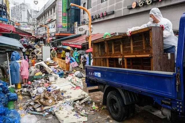 Workers clear debris at the historic Namseong Market in the Gangnam district of Seoul on August 9, 2022, after record-breaking rains caused severe flooding, with at least seven people dead and seven more missing, officials said. (Photo by Anthony Wallace/AFP Photo)