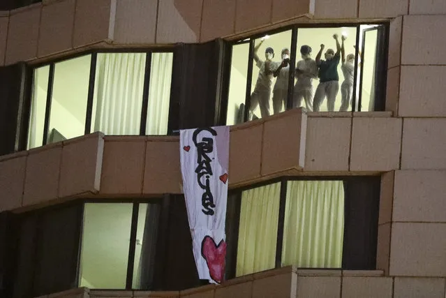 Health workers are seen as a sign reading “Thank you” hangs from a window at a hospital, amid the spread of the coronavirus disease (COVID-19), in Barcelona, Spain on April 14, 2020. (Photo by Nacho Doce/Reuters)