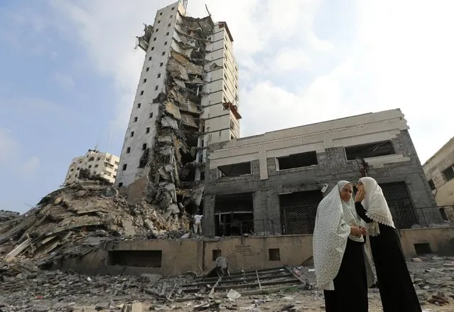 Palestinian women stand next to the remains of one of Gaza's tallest apartment towers, which witnesses said was hit by an Israeli air strike that destroyed much of it, in Gaza City August 26, 2014. (Photo by Mohammed Salem/Reuters)