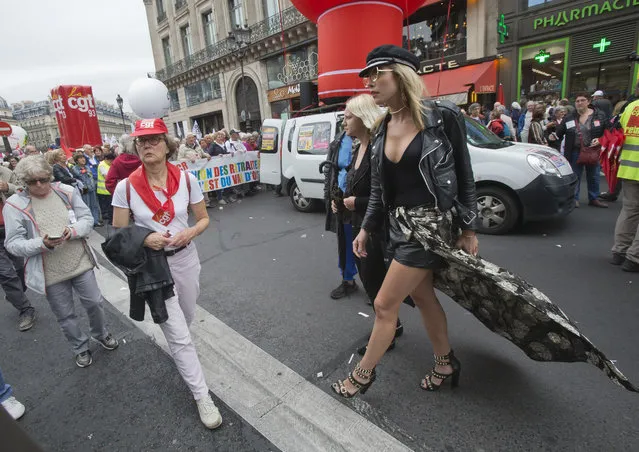 A fashion lover who rushes to Balmain fashion show, crosses the rally of pensioners in Paris, France, Thursday, September 28, 2017. Thousands of retired French workers have staged protests in Paris and around France over a new tax hike on their pensions and other policies by President Emmanuel Macron's government. (Photo by Michel Euler/AP Photo)