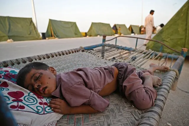 Houseflies sit on the face of an internally displaced flood-affected boy sleeping outside his tent at a makeshift camp after heavy monsoon rains in Sukkur, Sindh province on September 5, 2022. Nearly a third of Pakistan is under water – an area the size of the United Kingdom – following months of record monsoon rains that have killed 1,300 people and washed away homes, businesses, roads and bridges. (Photo by Aamir Qureshi/AFP Photo)