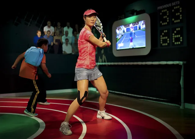 A student plays with a motion-controlled tennis games near a wax figure of Chinese tennis player Li Na on display at the Madame Tussauds Museum in Beijing, China Friday, September 19, 2014. Li Na, a two-time Grand Slam champion from China who took tennis in Asia to a new level, has retired due to recurring knee injuries. (Photo by Andy Wong/AP Photo)