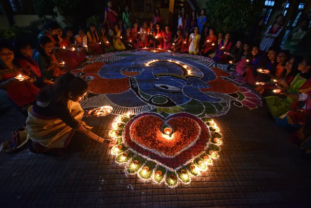 Students pose after lighting oil lamps around a “Rangoli”, a traditional pattern made from coloured powders and flower petals outside their hostel to celebrate Diwali, the Hindu festival of lights, in Guwahati, India, October 19, 2017. (Photo by Anuwar Hazarika/Reuters)