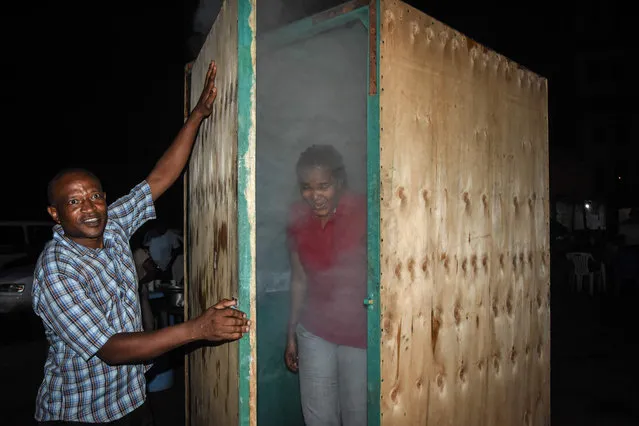 A woman leaves the steam inhalation booth installed by Tanzanian herbalist Msafiri Mjema in Dar es Salaam, Tanzania, on May 22, 2020 after using the treatment as a preventive measure against COVID-19 coronavirus. People willing to undergo the treatment will pay 1000 Tanzanian shillings (about less than a half a US dollar) to enter the booth, and inhale vapours of water and salt, for 5 to 10 minutes. Steam inhalations are a popular traditional treatment for flu, high fever, and malaria. Tanzania’s President John Magufuli said that one of his children had contracted COVID-19 coronavirus and had recovered thanks to steam inhalations using lemons and ginger. (Photo by Ericky Boniphace/AFP Photo)