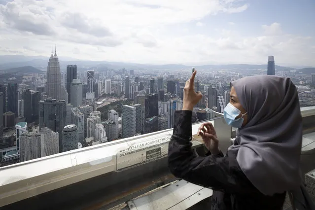 Tourist wearing a face mask takes picture at observation deck at Kuala Lumpur Tower in Kuala Lumpur, Malaysia, Wednesday, July 1, 2020. Malaysia entered the Recovery Movement Control Order (RMCO) after three months of coronavirus restrictions. (Photo by Vincent Thian/AP Photo)