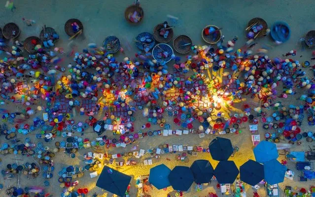 Food shoppers gather at an early morning fish market on a Southern Asia beach on June 15, 2020. The populated food outlet is seen from drone images directly above the crowd. Fisherman bring their catches, including shrimp, squid, crab, mackerel, tuna and anchovies onto the shallow water and sell directly to businesses and households in Tam Tien, Quang Nam Province, Vietnam. (Photo by Nguyen Sanh Quoc Huy/Triangle News)