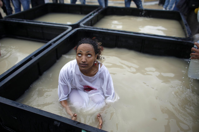 A Christian pilgrim dunks herself in water from the Jordan River during a ceremony at the baptismal site known as Qasr el-Yahud on the banks of the Jordan River near the West Bank city of Jericho January 18, 2011. (Photo by Nir Elias/Reuters)