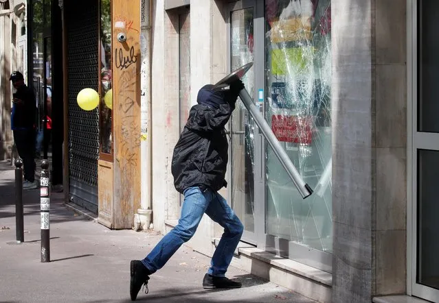 A man smashes a shop window as people of the “yellow vests” movement join a demonstration held by French health workers on the Bastille Day in Paris, as part of a nationwide day of actions to urge the French government to improve wages and invest in public hospitals, in the wake of the coronavirus crisis, in France, July 14, 2020. (Photo by Gonzalo Fuentes/Reuters)