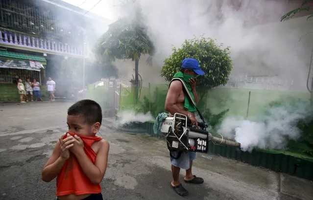 A boy covers his nose while a worker fumigates outside a residential area in Paranaque city, metro Manila September 26, 2015. The Department of Health has urged the public to increase their defenses against dengue after it recorded a 16.5-percent increase in the cases this year with a total of 78,808 people afflicted with dengue from January 1 to September 5, according to local media. (Photo by Romeo Ranoco/Reuters)