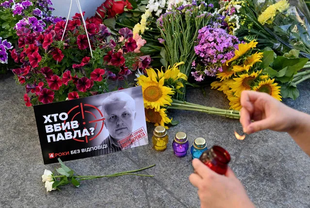 A person lights a candle at a memorial to journalist Pavel Sheremet on the site where Sheremet's car exploded on the 4th anniversary of his death in Kiev on July 20, 2020. Pavel Sheremet, a 44-year-old columnist for Ukrainska Pravda, dual Russian and Belarusian citizen, died when his car exploded in the center of Ukrainian capital of Kiev in 2016 in still unexplained circumstances. (Photo by Sergei Supinsky/AFP Photo)