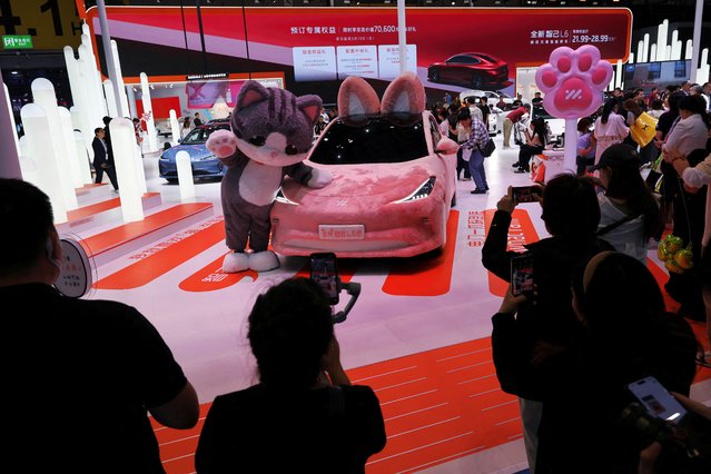 People take photos of a mascot and a concept car at the IM Motors booth during a media day for the Auto Shanghai show in Shanghai, China on April 24, 2025. (Photo by Go Nakamura/Reuters)
