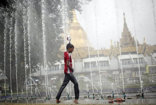 A boy play during rain fall near Sule Pagoda in Yangon, Myanmar September 18, 2015. (Photo by Soe Zeya Tun/Reuters)