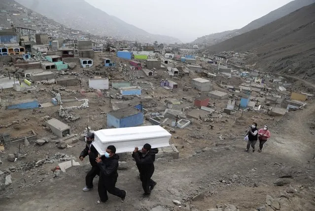 Cemetery workers carry the coffin that contains the remains of Wilson Gil, who family members say died of COVID-19 related complications, to a burial site at the Martires 19 de Julio cemetery on the outskirts of Lima, Peru, Wednesday, August 26, 2020. The South American country has the highest number of new coronavirus infections in Latin America after Brazil. (Photo by Martin Mejia/AP Photo)