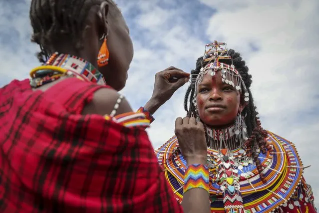 A Maasai woman adjusts the jewellery of another as they prepare to watch the Maasai Olympics in Kimana Sanctuary, southern Kenya Saturday, December 10, 2022. (Photo by Brian Inganga/AP Photo)