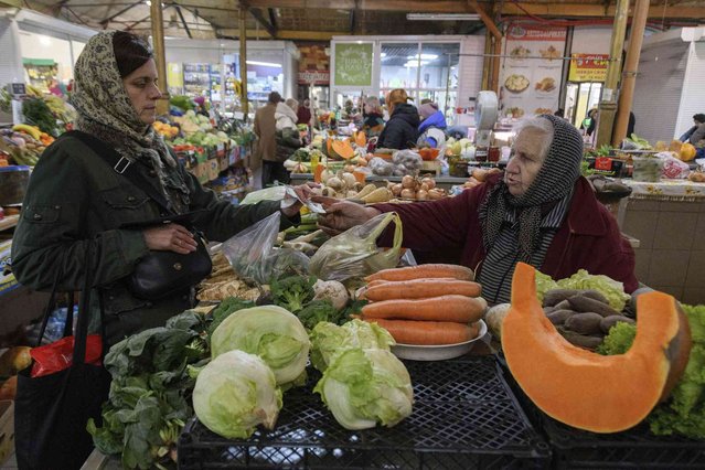 A woman buys vegetables in a market in Lviv, Ukraine, Monday November 11, 2024. (Photo by Mykola Tys/AP Photo)
