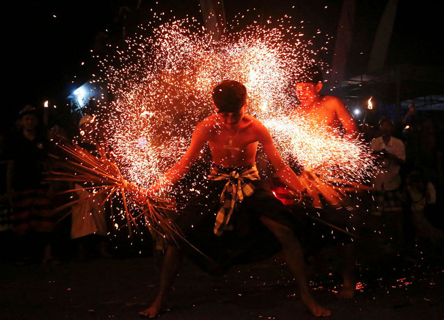 A Balinese man is hit with burnt dried coconut leaves during a fire fight ritual ahead of the holy day of Nyepi, which is a day of silence for self-reflection to celebrate the Balinese Hindu New Year in Paksebali village, Klungkung, Bali, Indonesia, on March 28, 2025. (Photo by Johannes P. Christo/Reuters)