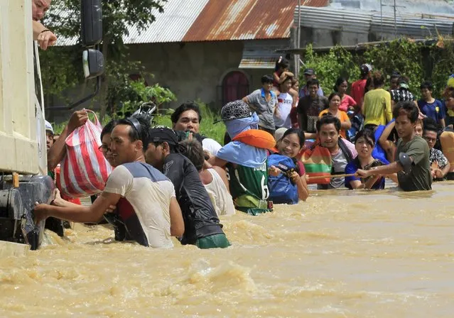 Residents hold on a rope while crossing flood waters brought by typhoon Koppu that battered Candaba town, Pampanga province, north of Manila October 20, 2015. (Photo by Romeo Ranoco/Reuters)