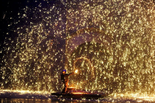 A performer sprays molten iron against a wall to create sparks during a traditional performance to celebrate Chinese Lunar New Year of the Dog in Zhangjiakou, Hebei province, China February 17, 2018. (Photo by Reuters/China Stringer Network)