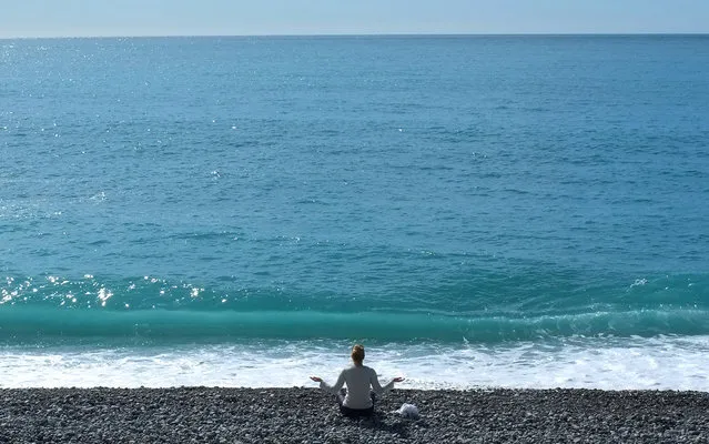 A woman gestures during a sun salutation, on the beach in Nice, southeastern France, Tuesday, March 19, 2013. (Photo by Lionel Cironneau/AP Photo)