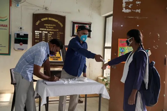 A student wearing a protective face masks gets her temperature checked at a government-run school after authorities ordered schools to reopen voluntarily for classes 9 to 12, amidst the coronavirus disease (COVID-19) outbreak, in Gurugram, India October 15, 2020. (Photo by Anushree Fadnavis/Reuters)