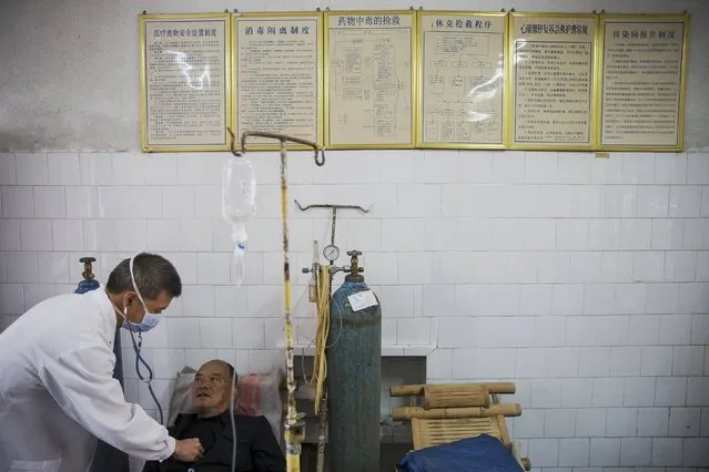 Fu Jianghua (L), the head of Yangjia Hospital, checks a patient in the hospital in Wuyi County, Zhejiang Province, China October 19, 2015. Fu Jianghua has worked at Yangjia Hospital since 1983, when it was operated by a local mine, he is now the hospital's head. (Photo by Damir Sagolj/Reuters)