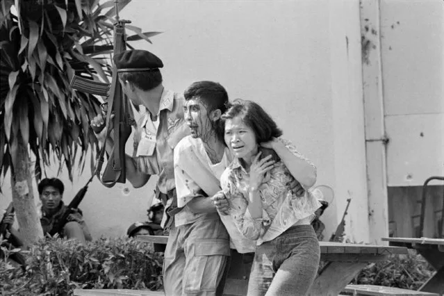 In this October 6, 1976 file photo blood streaming down his face, a leftist student, center, wounded and captured by police is helped to an ambulance at the Thammasat University campus in Bangkok, Thailand. (Photo by Neal Ulevich/AP Photo)