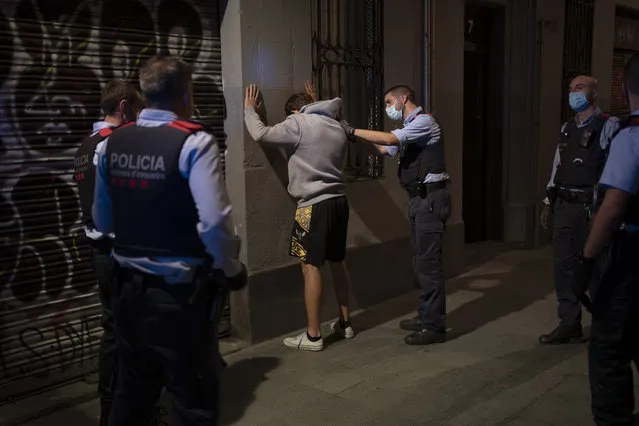 A man is detained by Mossos D'Esquadra, the regional police of Catalonia, after curfew in Barcelona, Spain, Sunday, November 1, 2020. Despite a large adherence to the recently re-imposed curfews in Spain, police patrolling Barcelona are still finding young people breaking the rules. (Photo by Emilio Morenatti/AP Photo)