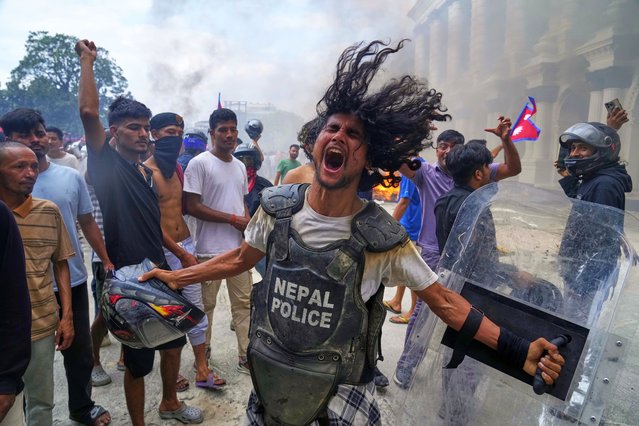 A protester wearing flak jacket and carrying a shield snatched from a policeman shouts slogans at the Singha Durbar, the seat of Nepal's government's various ministries and offices during a protest against social media ban and corruption in Kathmandu, Nepal, Tuesday, September 9, 2025. (Photo by Niranjan Shrestha/AP Photo)