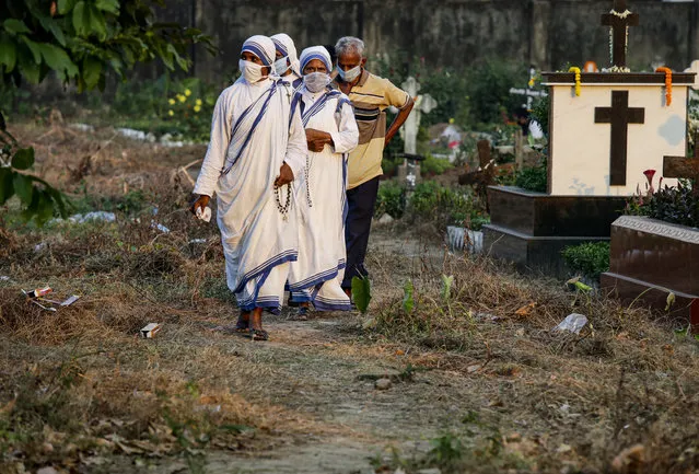 Nuns of the Missionaries of Charity, the order founded by Saint Teresa, wearing face masks as a precaution against the coronavirus walk along the graves of the deceased during All Souls Day in Kolkata, India, Monday, November 2, 2020. (Photo by Bikas Das/AP Photo)