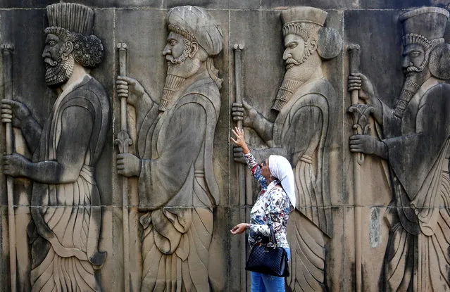A woman touches the wall of a Parsi fire temple featuring huge carvings of ancient priests on the occasion of the Persian New Year in Mumbai, India on March 21, 2018. (Photo by Francis Mascarenhas/Reuters)