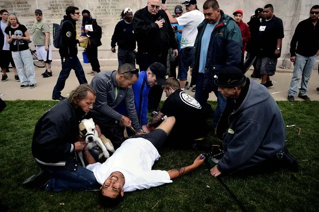 Denver Paramedics, Denver Police officers and good Samaritans  tend to a shooting victim at Civic Center Park after the 4/20 pot rally, Saturday, April 20, 2013 in Denver. Gunfire erupted at a Denver pot celebration Saturday, injuring two people and scattering a crowd of thousands who had gathered for the first 4/20 counterculture holiday since the state legalized marijuana. (Photo by Joe Amon/AP Photo/The Denver Post)