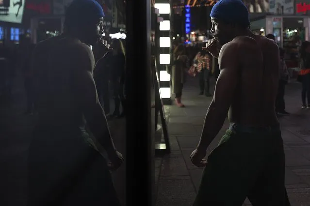 A man shadow boxes in a retail store window in Times Square, New York, November 24, 2014. (Photo by Carlo Allegri/Reuters)